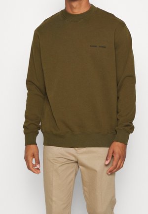 Sweatshirt vert olive à col rond, avec des poignets et un bas côtelés. Présente un petit logo noir sur la poitrine. Texture de tissu douce.