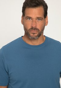 Modré bavlněné tričko s kulatým výstřihem, krátkými rukávy a hladkou texturou. Jednoduchý design, žádné vzory ani akcenty.