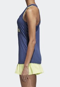 Marinblå ärmlös topp med gul krage, kombinerad med en limegrön, utsvängd kjol. Mjuk tygkvalitet, avslappnad design, lämplig för aktiv klädsel.