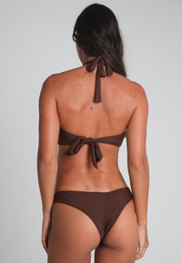 Brun bikini-set med halterneck-top med knytning i halsen och på ryggen, matchande lågmidjade bottnar med minimal täckning. Slät textur.