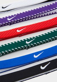 Bandas elásticas de Nike en varios colores: blanco, púrpura, rojo, verde, azul y negro. Cada una cuenta con un pequeño logo blanco y un diseño texturizado distintivo.