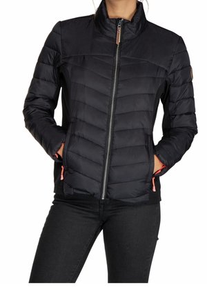 Black quilted zip-up jacket with stand collar, side pockets, and a person wearing black pants with hands in pockets.