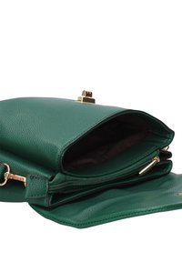 Borsa in pelle verde martellata con chiusura e cerniera dorate, parzialmente aperta che mostra un interno scuro e diversi scomparti.
