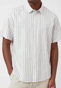 Chemise à manches courtes, boutonnée, de couleur beige clair avec de fines rayures verticales, fabriquée dans un tissu léger, avec un col pointu et un ourlet arrondi.