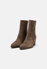 Brune ante støvletter med spiss tå, minimal sømdetalj og kraftig hæl. Glatt tekstur med en myk finish.