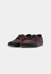 Zapatillas de lona a cuadros rojos y negros con suelas de goma negras, punta redonda y cordones negros. Diseño plano con mínimas marcas.