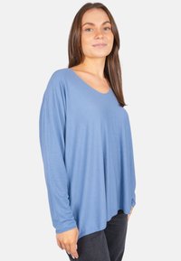 Langärmliges Oberteil in Hellblau, aus weichem Stoff mit V-Ausschnitt und lässiger Passform. Besitzt subtile strukturierte Details entlang der Ärmel.