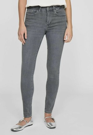Grå denim skinny jeans med en tætsiddende pasform, der har en høj talje, fem lommer og subtil falming. Parret med sølvfarvede flade sko.