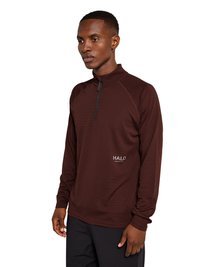 Mand iført en langærmet, vinrød quarter-zip trøje med teksten "HALO" nær taljen, kombineret med sorte bukser, stående mod en hvid baggrund.