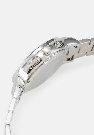 Silver stainless steel watch with a smooth, rounded case, textured crown, and a strap featuring linked segments. Simple, unmarked back.