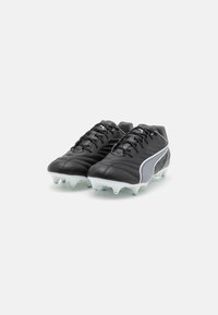 Scarpe da football nere con tomaia in pelle texture, dotate di una striscia bianca di accento, lacci e suola con tacchetti bianchi per la trazione.
