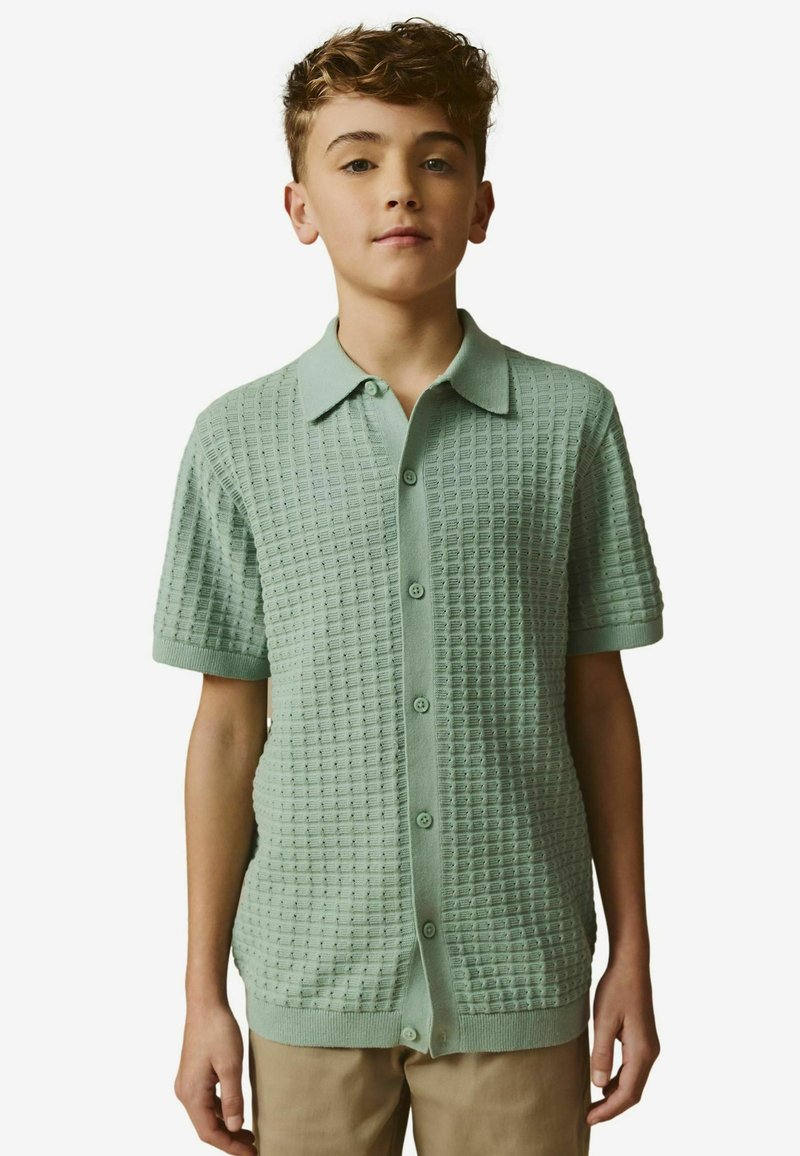 Kurzarm-Mintgrün Poloshirt mit einem strukturierten Karomuster, Knopfverschluss vorne und flachem Kragen. Glattes Strickmaterial.
