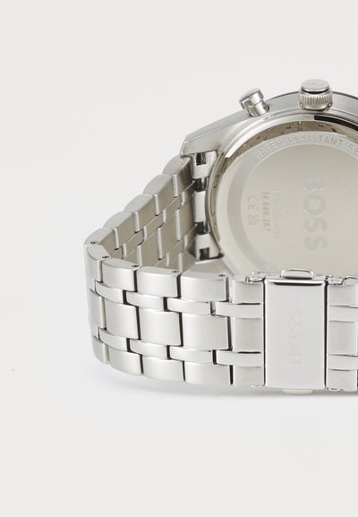 Montre-bracelet en métal argenté avec un bracelet à maillons, un boîtier rond et le nom de la marque gravé au dos ; design résistant à l'eau.
