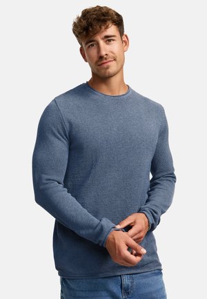 Blauses langärmliges Shirt mit einem strukturierten Strickmuster, Rundhalsausschnitt und taillierten Ärmeln, kombiniert mit blauen Jeans.