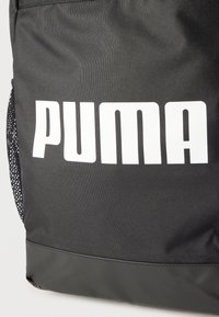 Μαύρο υφασμάτινο σακίδιο με μεγάλο λευκό λογότυπο PUMA και δίχτυ στην πλευρική τσέπη.