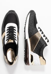 Black and gold athletic sneakers with a mesh and textured leather upper, white accents, and a transparent air-cushioned sole.