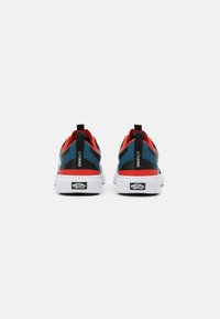 Ténis pretos e azuis com detalhes em vermelho, parte superior em malha, solas brancas grossas e alças de puxar. Apresenta a marca "ULTRARANGE" nas laterais.