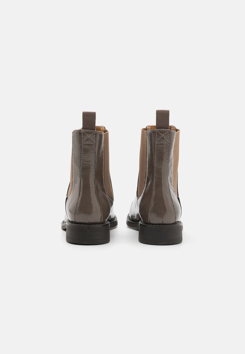 Braune Leder-Ankle Boots mit glänzender Oberfläche, elastischen Seitenpaneelen und Zuglaschen. Flache Sohle, runde Zehen und kontrastrierende Texturen.