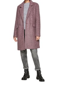 Cappotto in misto lana viola con revers a scollo a V, due bottoni, tasche laterali e vestibilità comoda, abbinato a un maglione grigio e jeans sbiaditi.