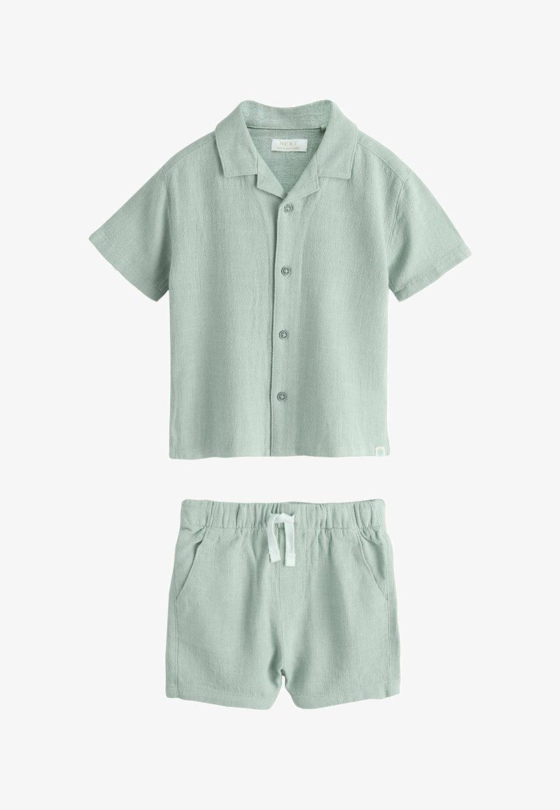 Camisa de manga corta color verde claro con botones y cuello, combinada con pantalones cortos a juego con cintura elástica, cordón blanco y bolsillos laterales.