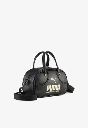 Melnas ādas somiņa ar divām rokturiem, rāvējslēdzēja aizdari un noņemamu siksnu. Uz somas ir liels balts "PUMA" logotips un gluda tekstūra.