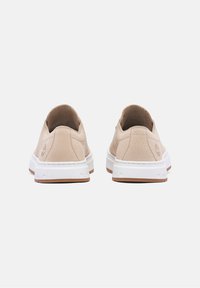 Beige lädersneakers med en texturerad yta, vit gummisula och bruna detaljer. Har en logotyp präglad på hälen.
