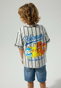 Camicia a maniche corte in cotone a righe con personaggi di Pokémon. I colori includono grigio, blu, giallo e arancione. Il testo dice "Pokémon."