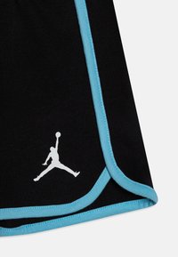 Pantaloni sportivi neri con bordi azzurri, caratterizzati da un logo Jordan bianco. Realizzati in un tessuto morbido e elasticizzato, progettati per l'abbigliamento sportivo.