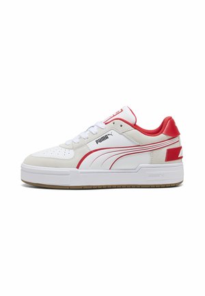 Låga vita Puma-sneakers med röda detaljer, vita snören, perforerad tå och tjock vit sula med gummisula.