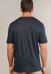 Mörkblå kortärmad t-shirt med rund halsringning, med en subtil struktur och avslappnad passform, synlig sömnad längs fållen och ärmarna.