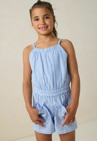 Combinaison à rayures bleues et blanches avec bretelles spaghetti réglables, taille élastique et poches volantées, confectionnée dans un tissu léger.