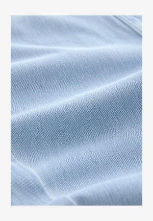 Țesătură denim albastru deschis cu o textură moale și un model de țesătură diagonală vizibil, cu o suprafață netedă, uniformă și o ușoară strălucire.