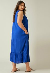 Blaues ärmelloses Maxikleid mit gerafftem Textur, Seitentaschen und einem gestuften Volantabschluss. Aus leichtem Stoff gefertigt.