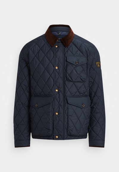 Marineblauer Steppjacke mit braunem Cordkragen, ausgestattet mit goldfarbenen Druckknöpfen, vier Fronttaschen und einem Logopatch am linken Ärmel.