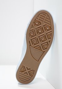 Semelle en caoutchouc bleu clair avec motif en losange, accents bruns texturés et logo "Converse All Star". Bords lisses et design flexible.