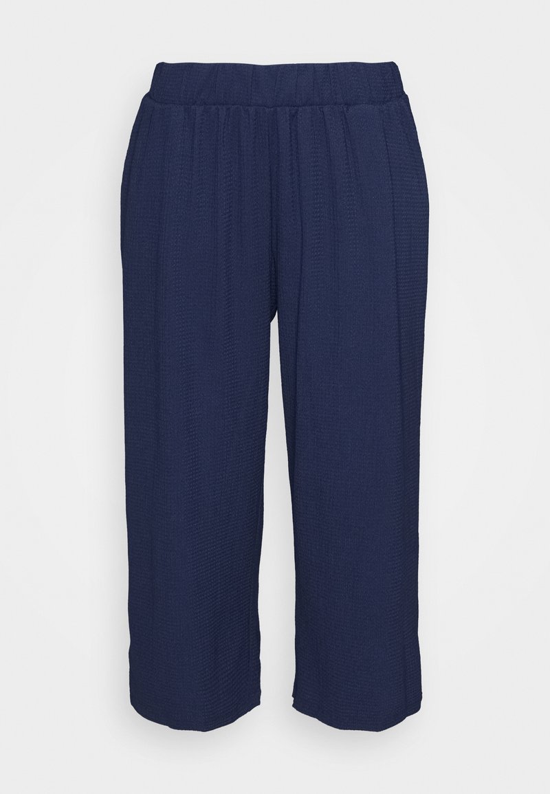 Pantalon large bleu marine avec taille élastique et tissu texturé, présenté sur un fond clair uni.