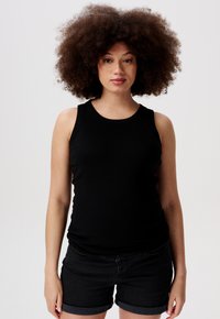 Svart ribbad tanktop med rund halsringning och breda axelband, kombinerad med mörka denimshorts med uppvikta nederkant.