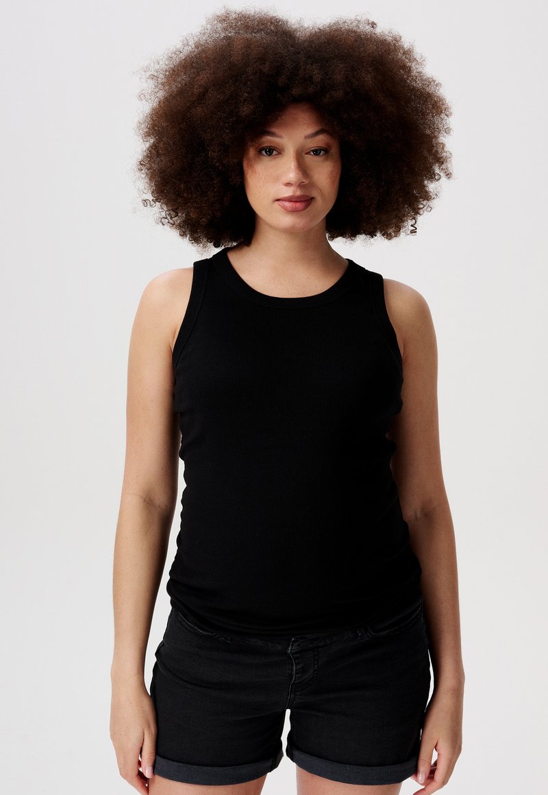 Svart ribbad tanktop med rund halsringning och breda axelband, kombinerad med mörka denimshorts med uppvikta nederkant.