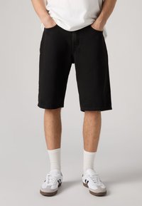 Črne denim kratke hlače z ohlapnim krojem, klasičnim dizajnom s petimi žepi, kontrastnim šivanjem in ravnim rezom tik nad kolenom.