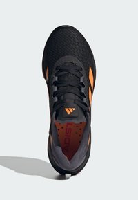 Black athletic shoe with orange accents, featuring a textured mesh upper, lace closure, and padded collar. Notable branding on the tongue.