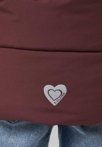 Bordoo kangasteste jämeda tekstuuriga jakk, millel on hõbedane südame logo ja tekst "S. OLIVER". Disain sisaldab horisontaalset õmblust.