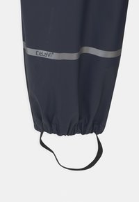 Marine regenbroek met elastische boorden en zwarte band; heeft een zilveren horizontale streep en het 'Celavi' logo gedrukt. Glad, waterdicht materiaal.
