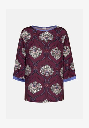 Haut couleur vin avec des motifs floraux en crème, bleu et rose. Présente des manches trois-quarts et un accent bleu à l'ourlet. Tissu doux.