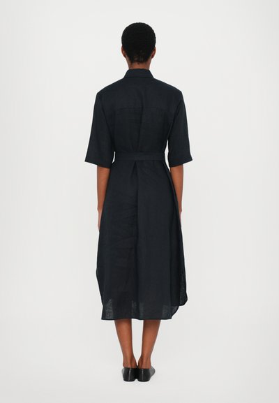 Vestido preto de linho com mangas curtas, cintura cinto e um ajuste descontraído. Apresenta uma pala nas costas e fendas laterais para maior liberdade de movimento.