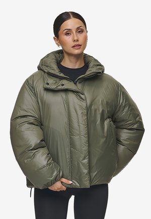Olijfgroene pufferjas met een capuchon, voorzien van een ritsluiting, gewatteerde textuur en een oversized pasvorm. Middenlang met aanpassingsmogelijkheden.