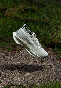 Light gray athletic shoe with a textured mesh upper, a sleek design, rubber sole, and minimal branding on the side.