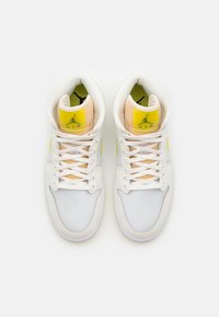Pair of white and yellow high-top Air Jordan sneakers with laces, cushioned collars, and Jumpman logo on tongues.