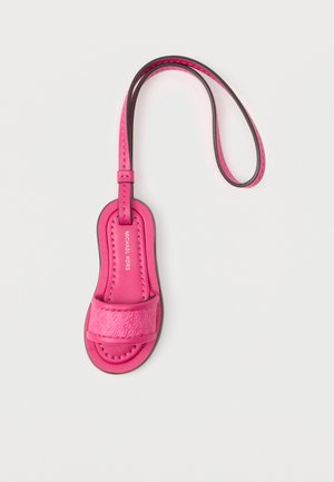 Klein roze leren bagagelabel in de vorm van een sandaal met bandje en Michael Kors-logo.