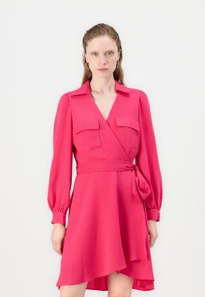 Rosa omslagkjole med lange pufferm, to brystlommer, et belte i midjen og en asymmetrisk underkant. Glatt stoffstruktur.