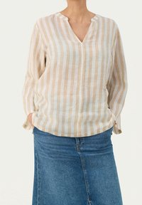 Blusa a righe leggera in crema e beige, con scollo a V, maniche lunghe e vestibilità comoda, abbinata a una gonna di jeans.